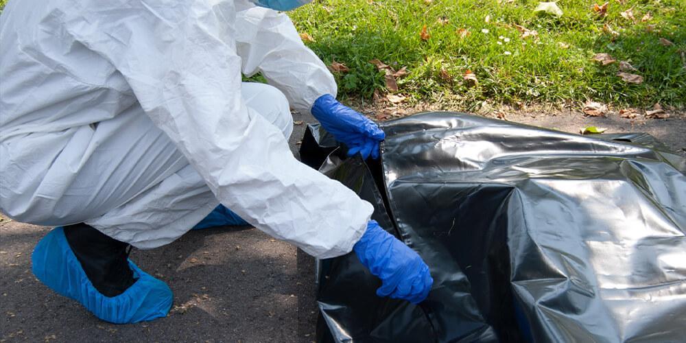 A victim at a crime scene being placed in a body bag